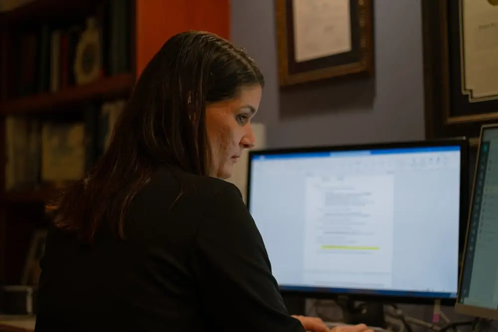 Woman sitting in front of a desk while browsing on the computer