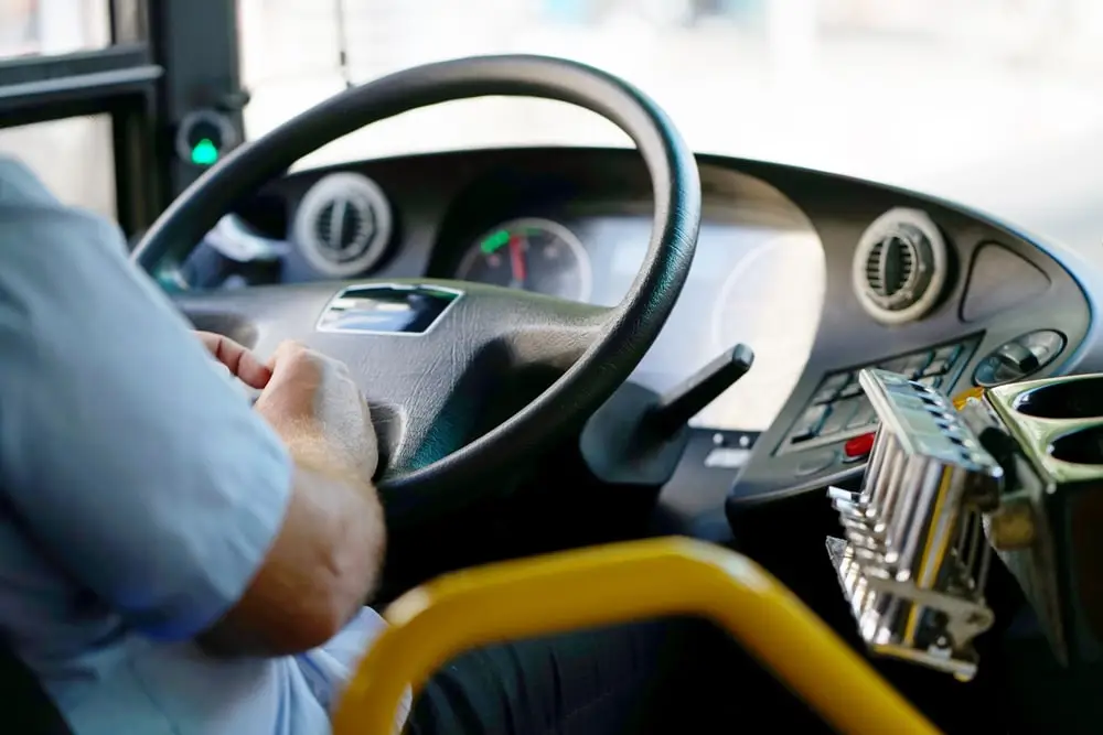 Hands of driver in a modern bus actively driving