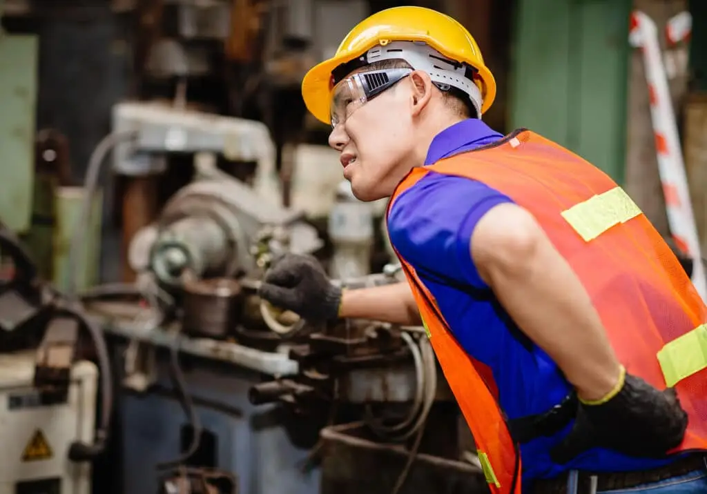 Worker working hard in industrial factories suffer from back waist pain while working on machines.