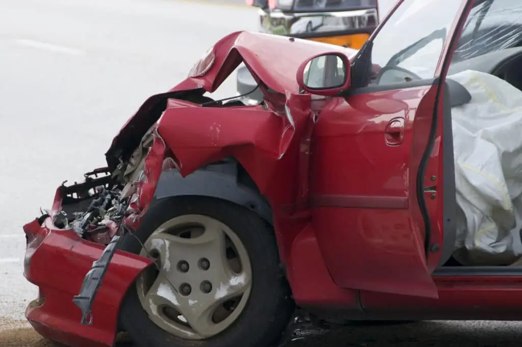Red vehicle with smashed front end showing air bag deployment