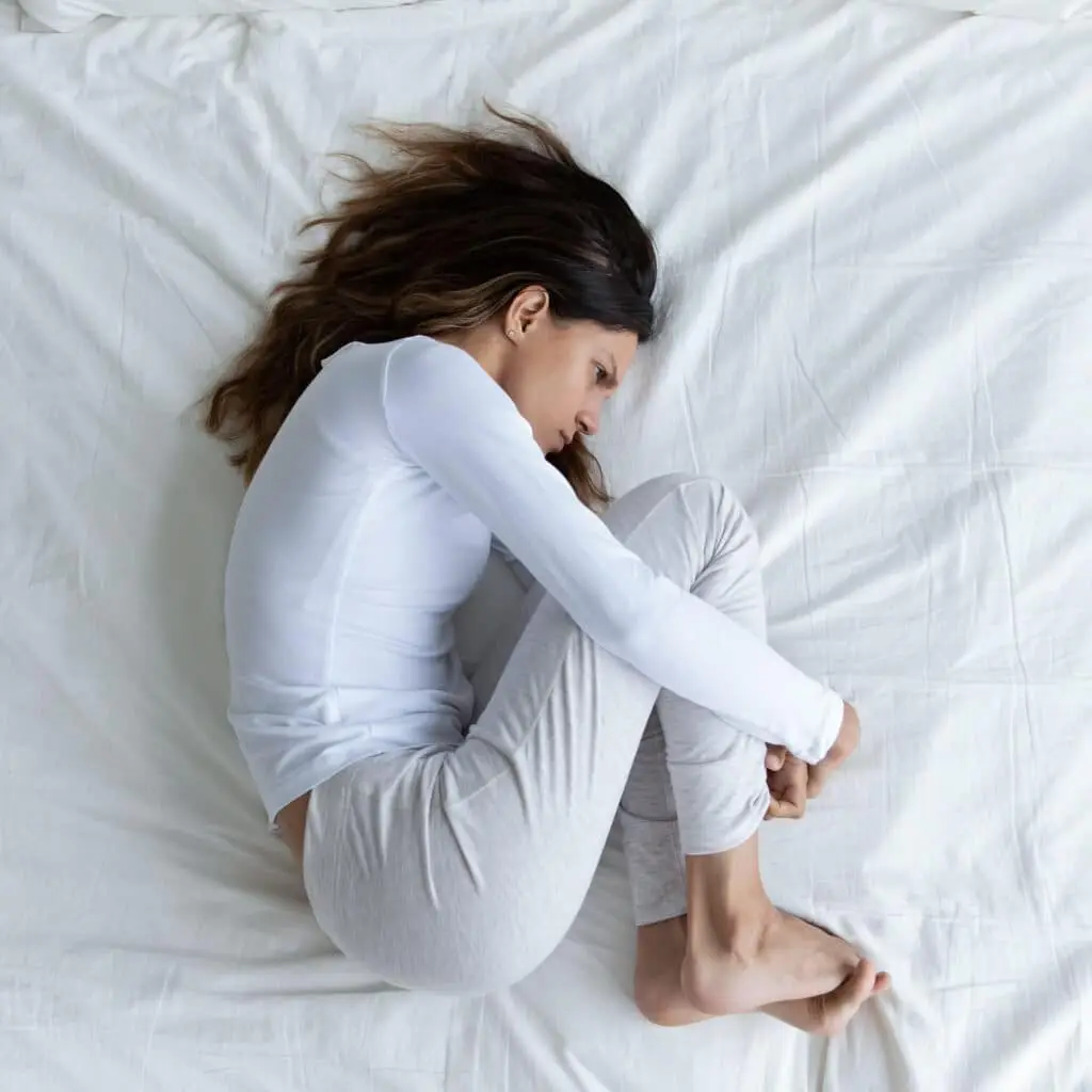 Top view depressed woman hugging knees