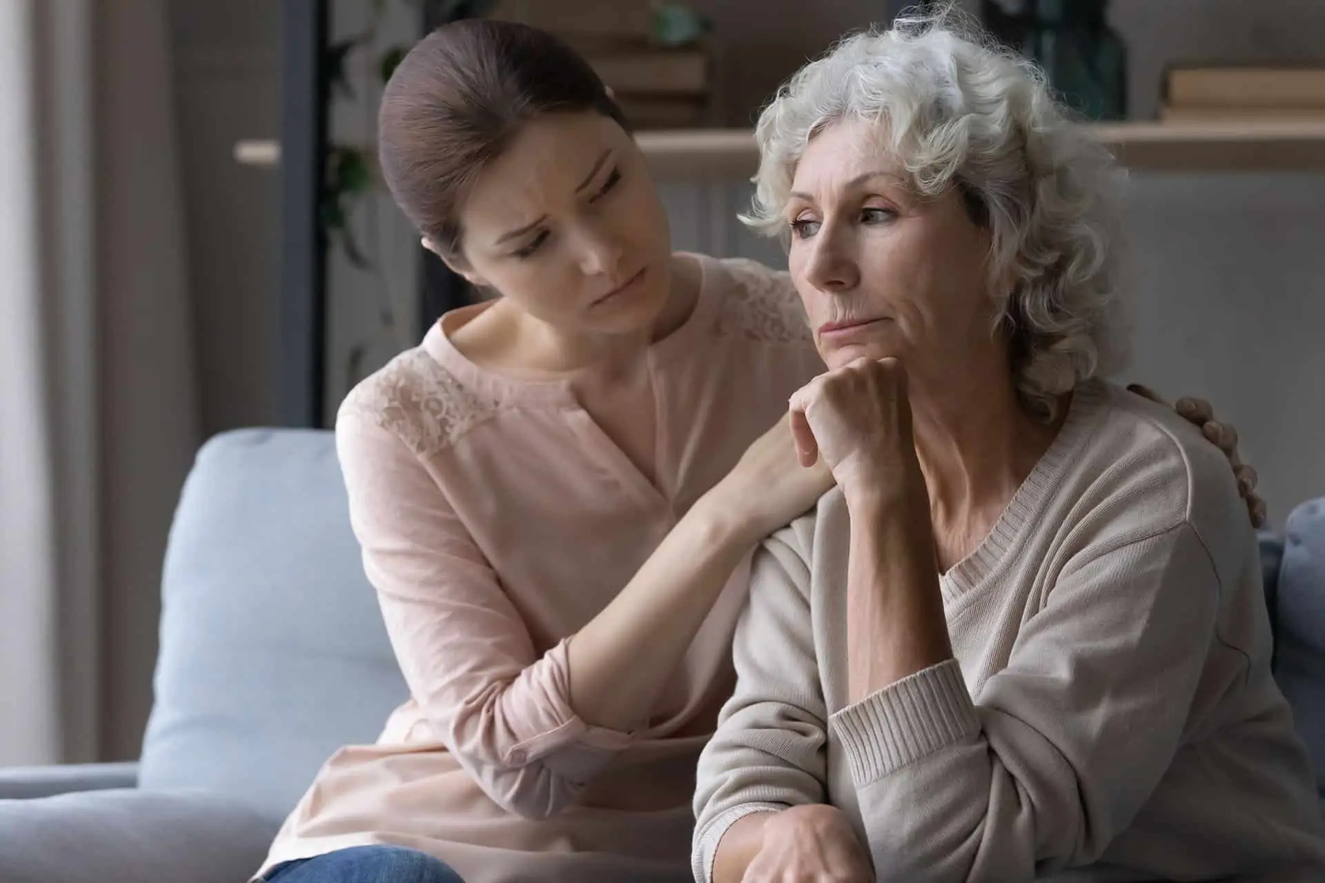 Young female caregiver support grieving suffering mature old woman