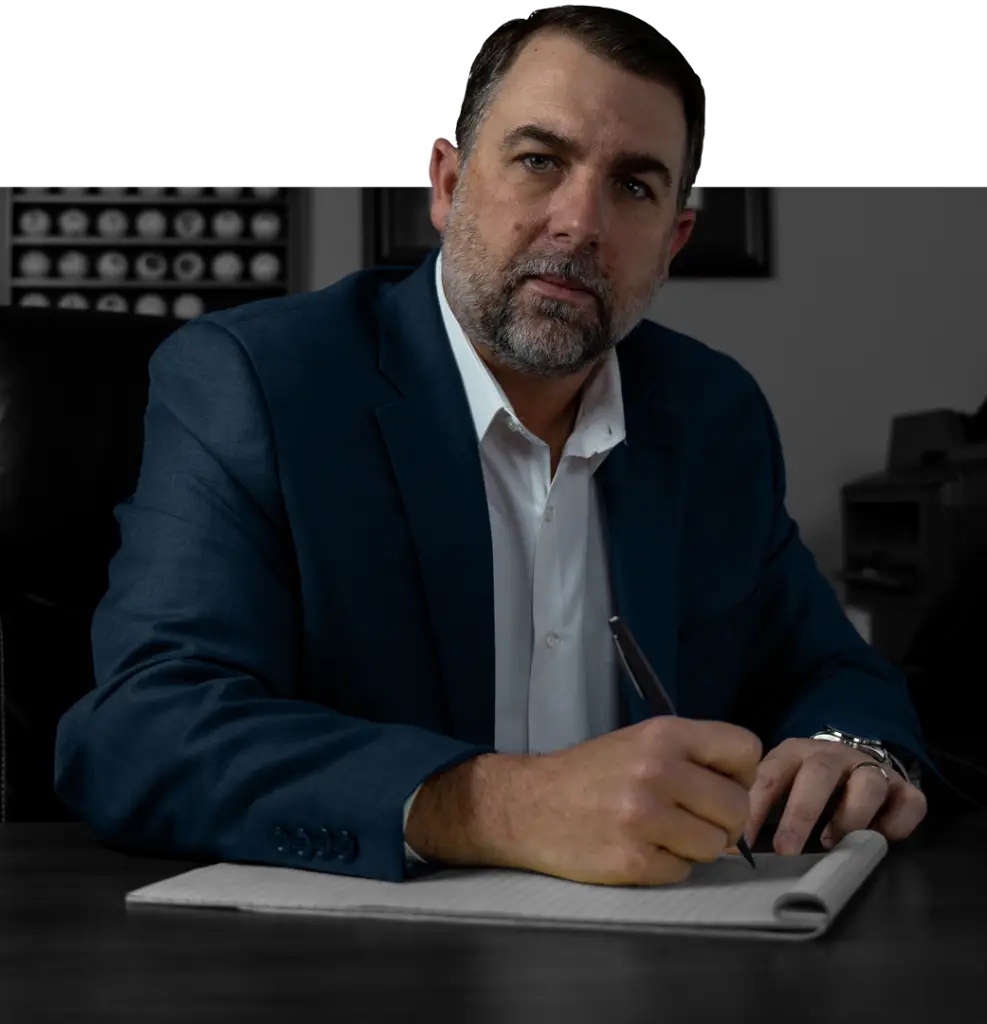 Man in suit working at a desk signing papers