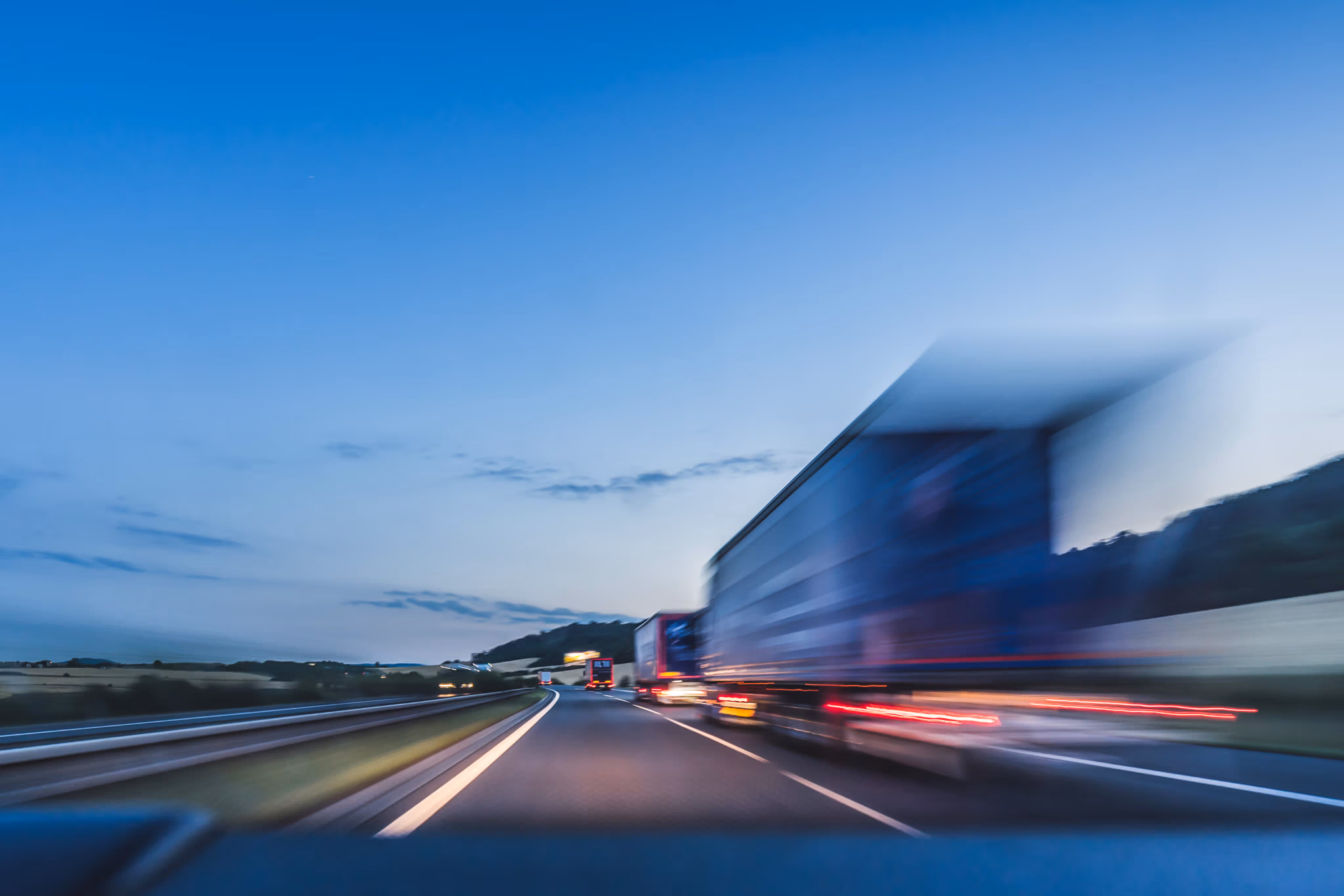 18-wheelers traveling on a highway at dusk, representing the dangers of commercial truck traffic