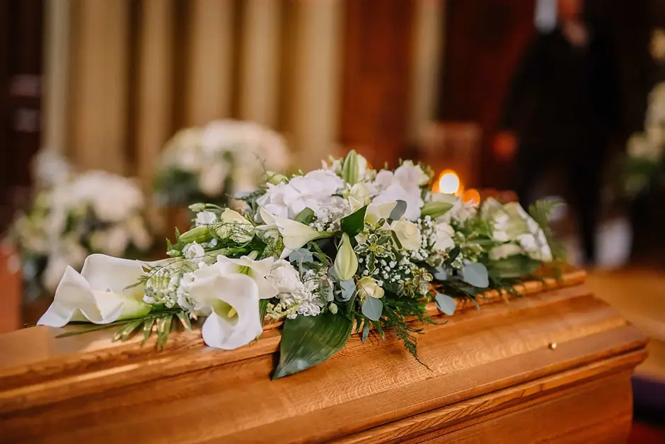 A coffin decorated with many flowers and candles in a beautiful church