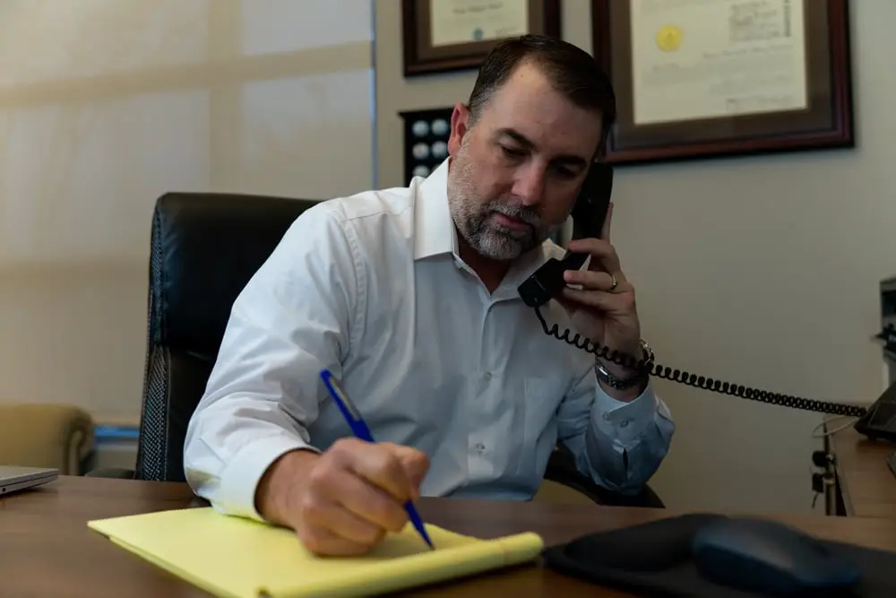Man writing something down while talking on the phone