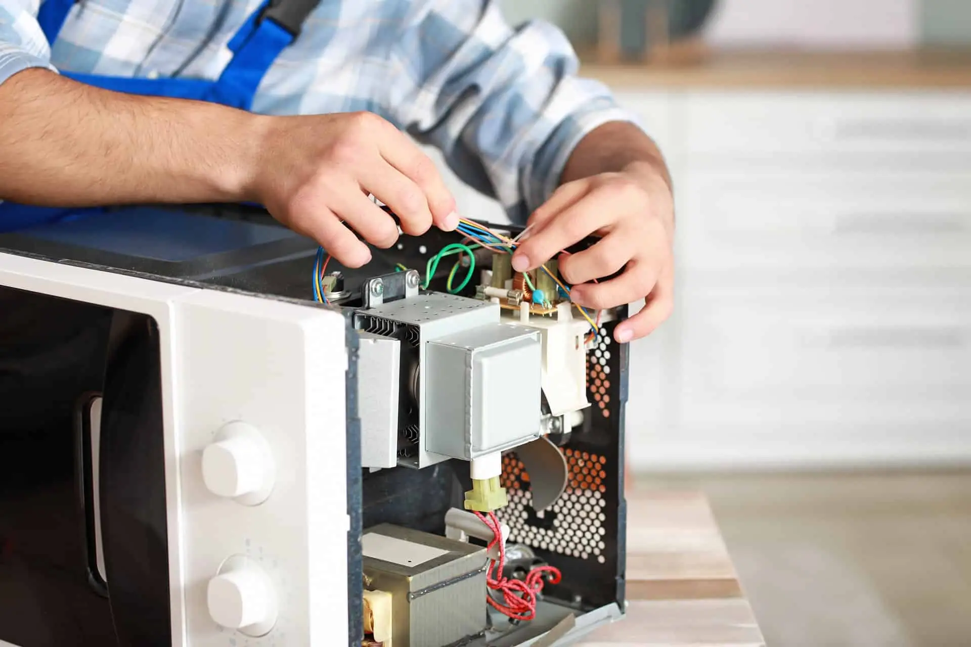 Worker repairing microwave oven in kitchen