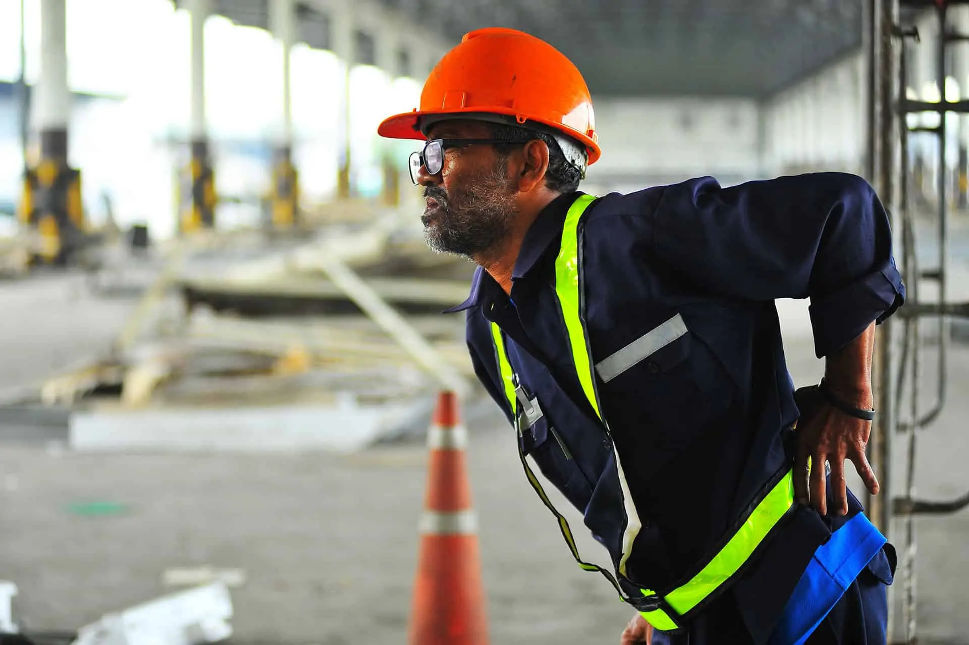 Senior worker with backache at construction site in warehouse.