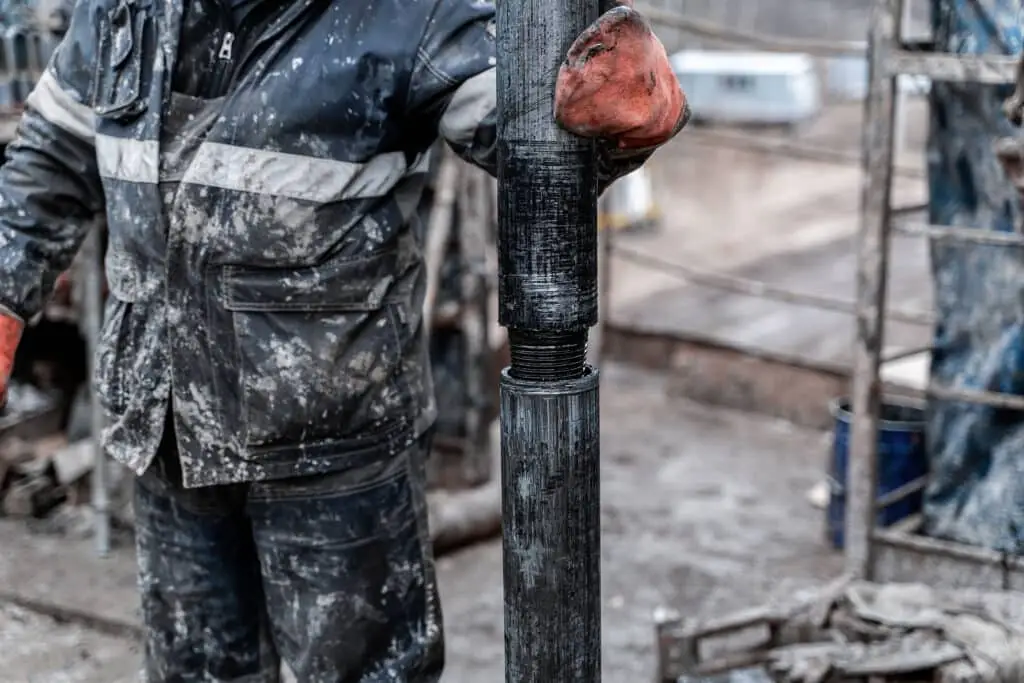 Work driller in red uniform, in helmet and goggles.