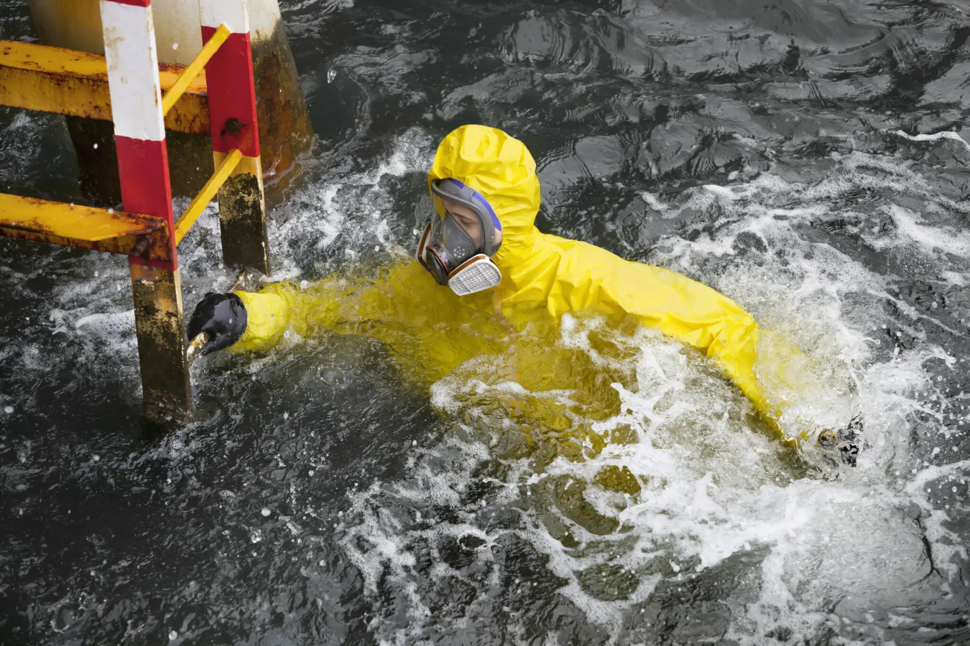 Maritime worker in protective gear in open water near platform structure