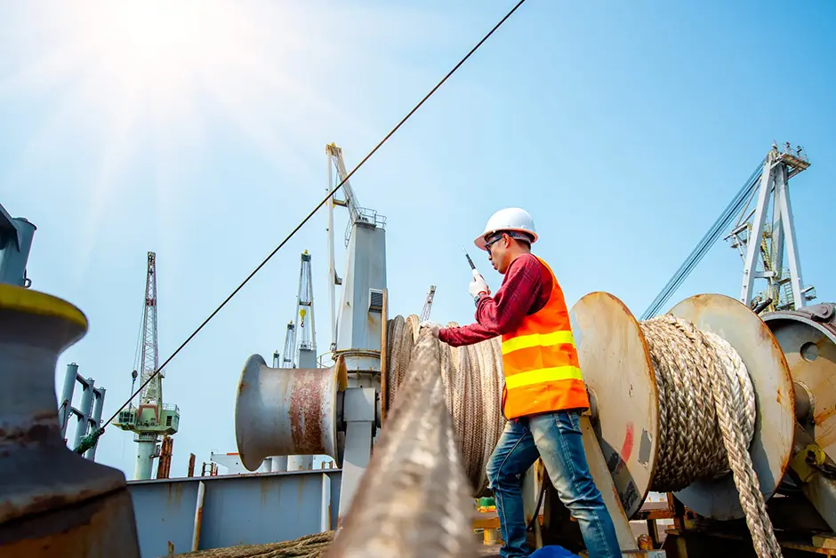 maritime worker touching a metal cable mooring on a ship at port