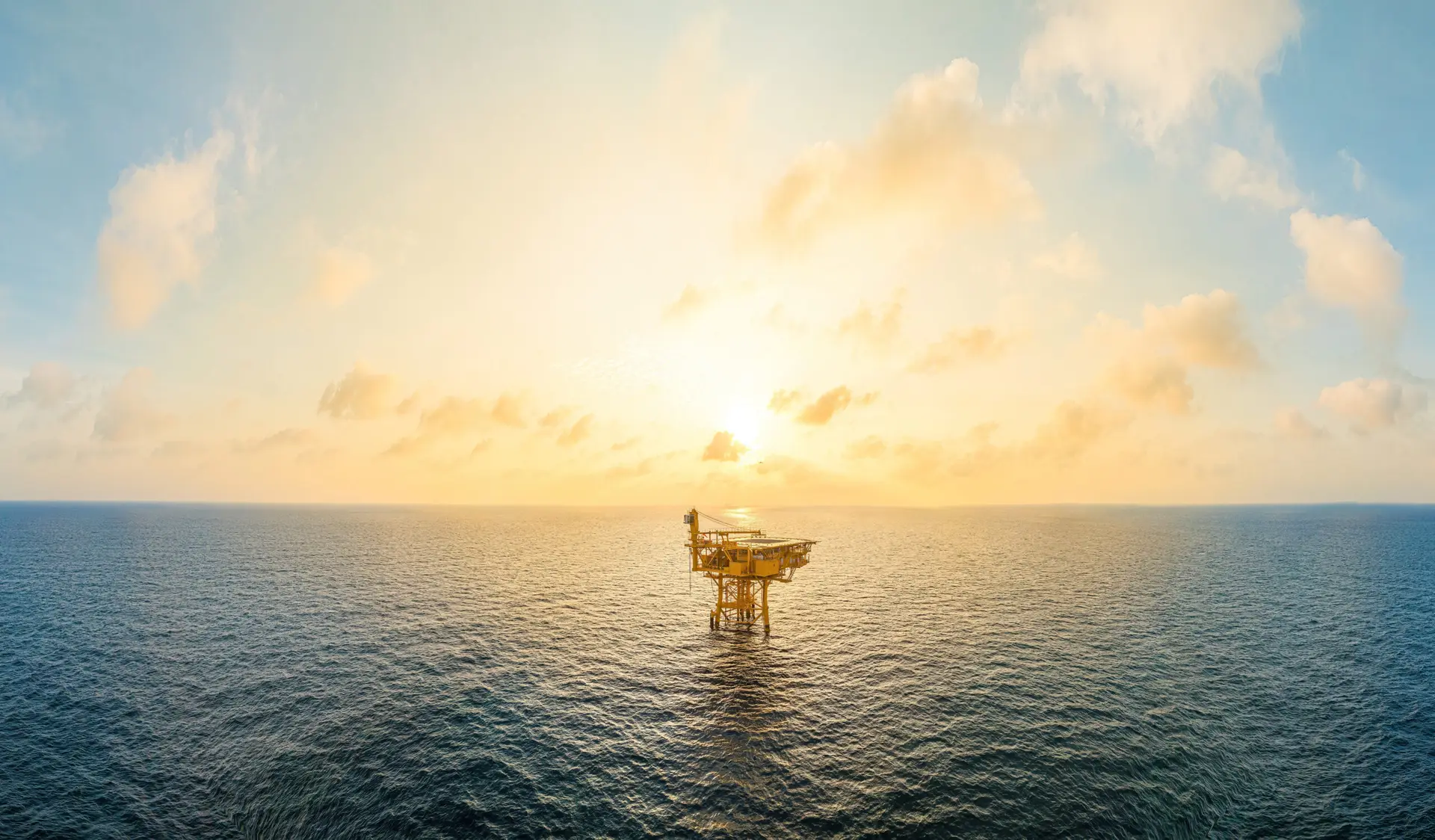 A huge yellow of offshore oil rig drilling platform in the gulf in sunset