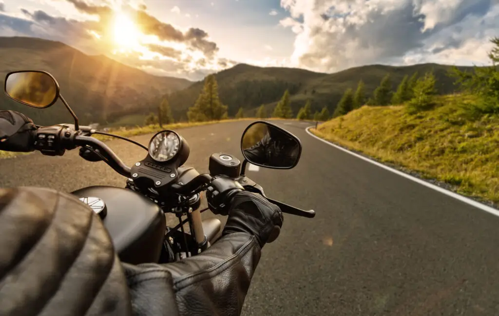 Point of view photo of a motorcycle rider on an open highway in green mountainous terrain