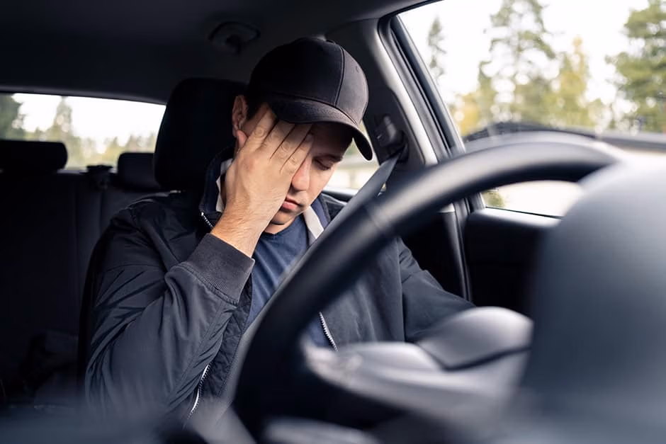 a man sitting behind the steering wheel of a vehicle