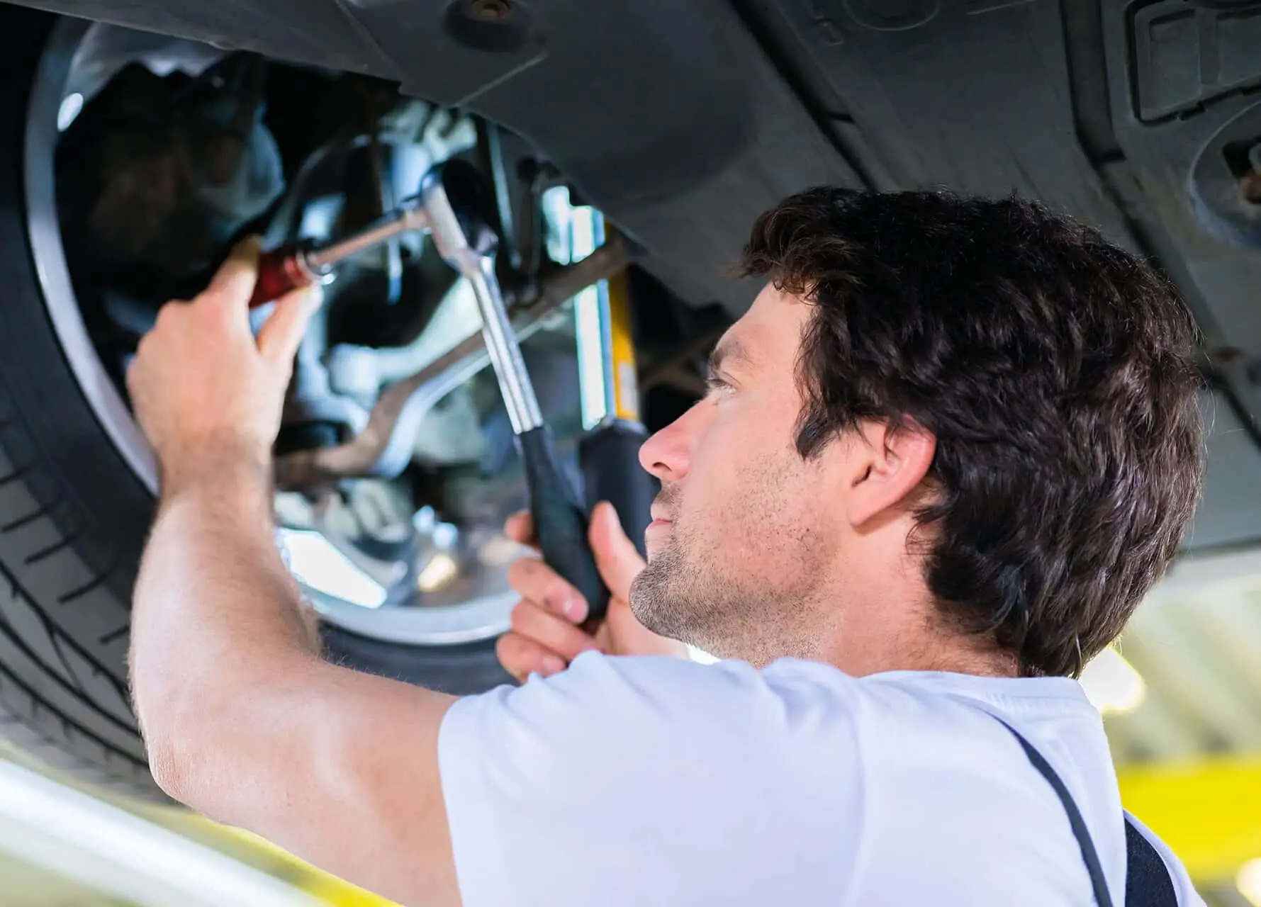 Mechanic working in car workshop on wheel